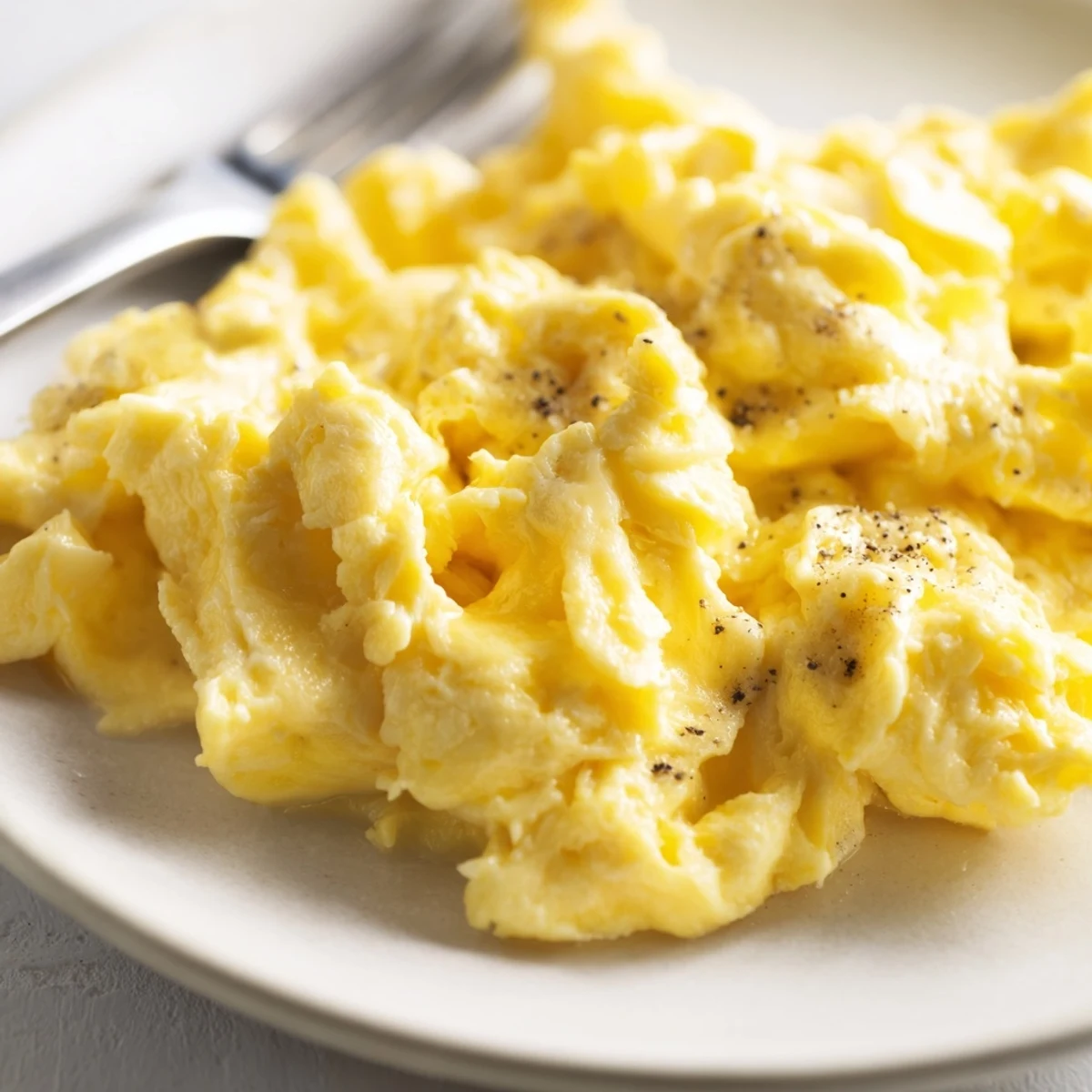 Creamy scrambled eggs piled on a plate with buttery golden curds