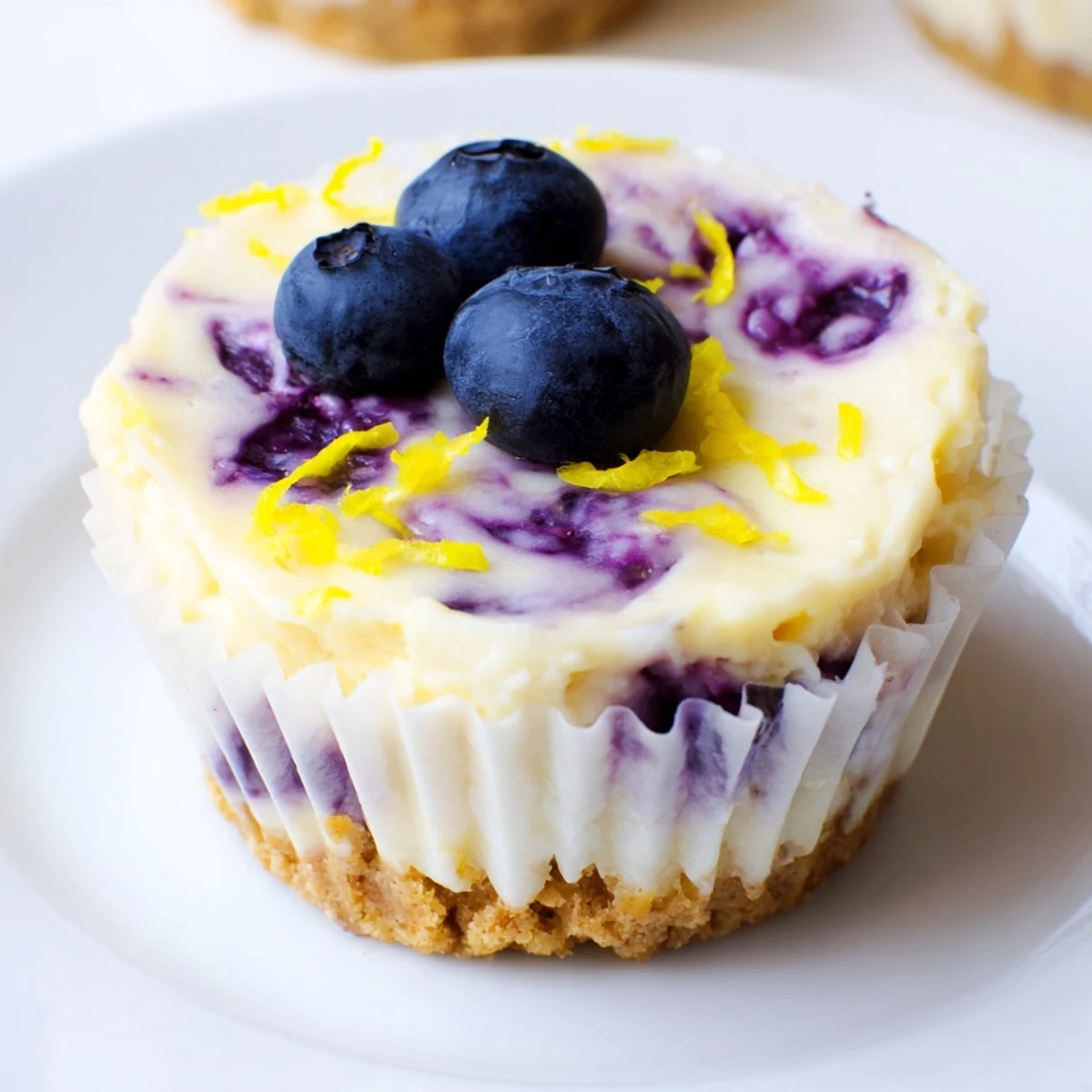 Creamy mini lemon blueberry cheesecakes with golden graham crusts and vibrant berry topping