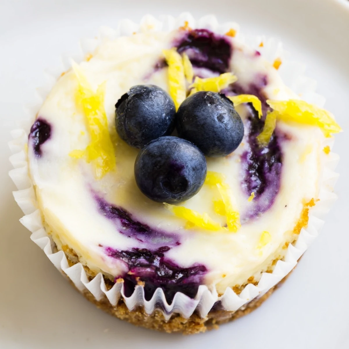 Mini lemon blueberry cheesecakes topped with swirled compote served on a white platter