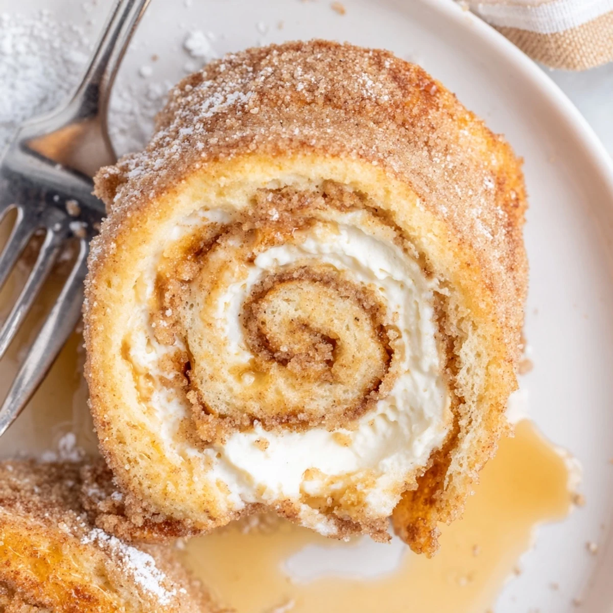Close-up of Cinnamon Roll French Toast Roll Ups sizzling in skillet, powdered-sugar dusted
