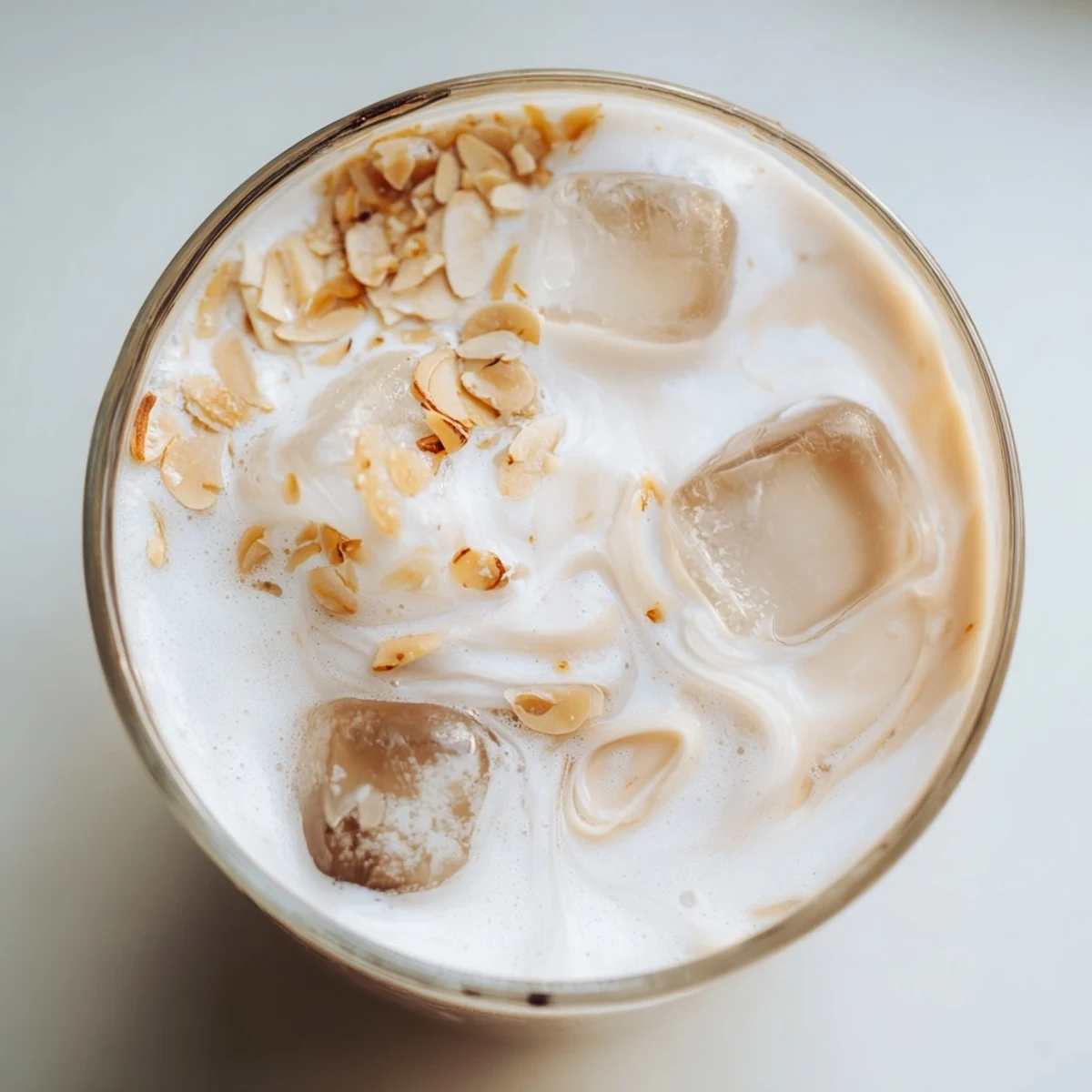 Creamy refreshing summer roasted almond milk beverage garnished with almond slivers and ice in a chilled glass