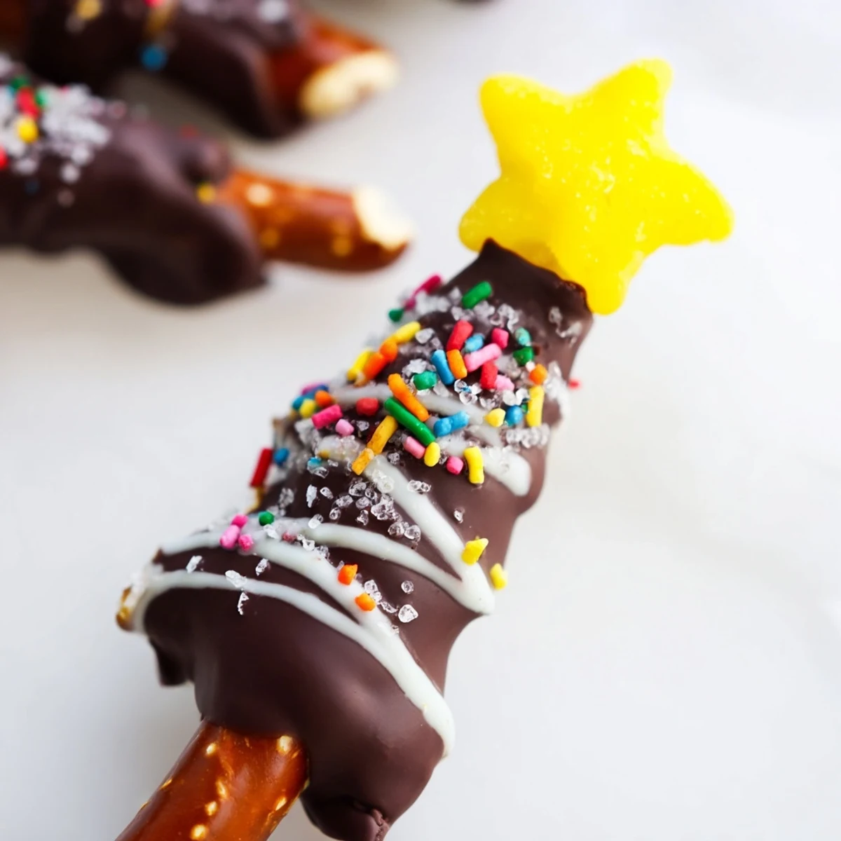 Festive chocolate pretzel trees coated in melted chocolate with colorful sprinkles and candy star toppers