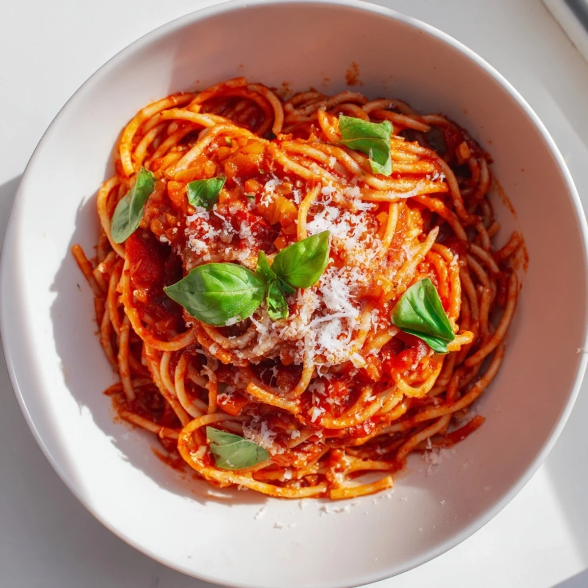Golden Parmesan-topped pasta noodles coated in rich homemade tomato sauce served on white ceramic plate