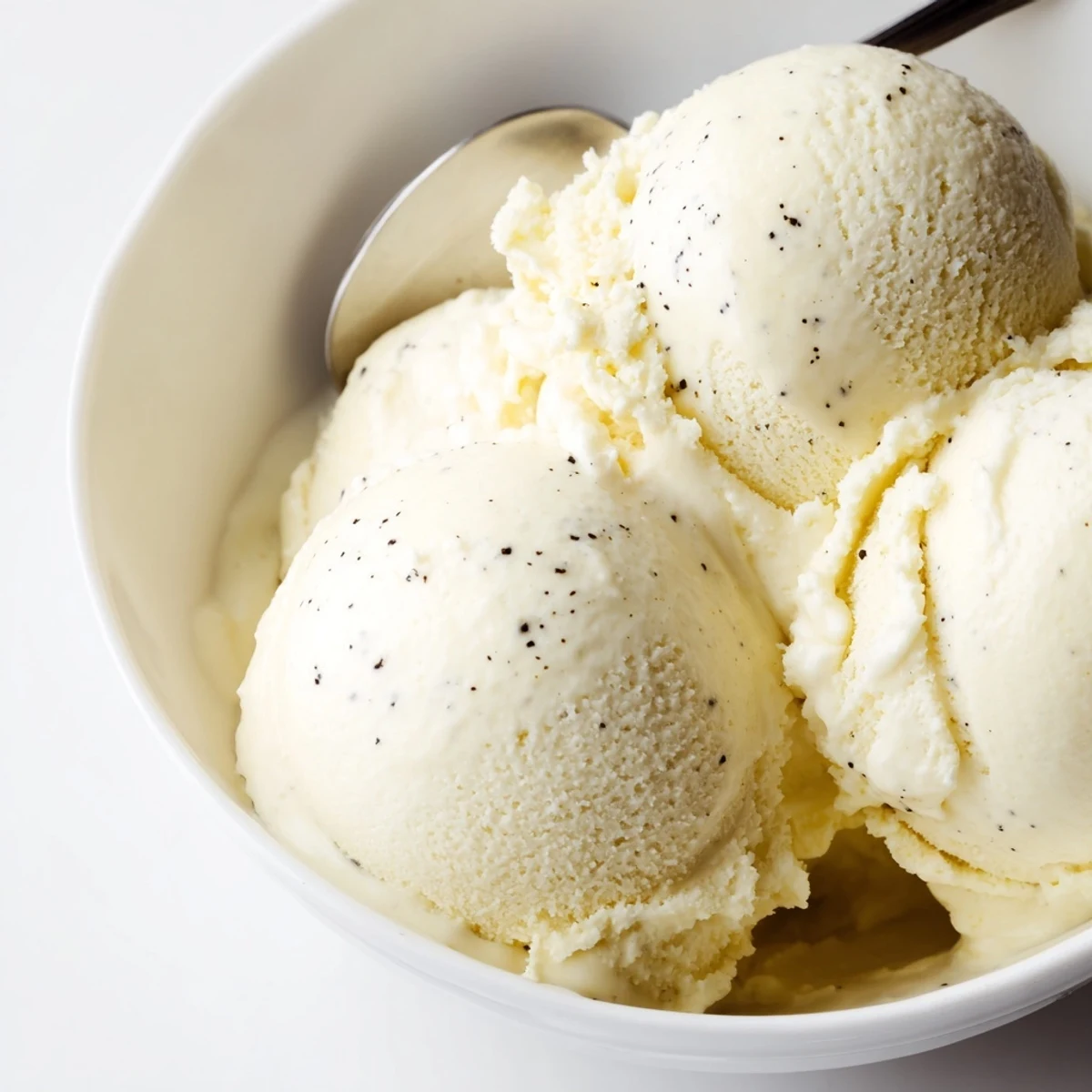 Creamy homemade vanilla ice cream served in a chilled glass bowl with a silver spoon
