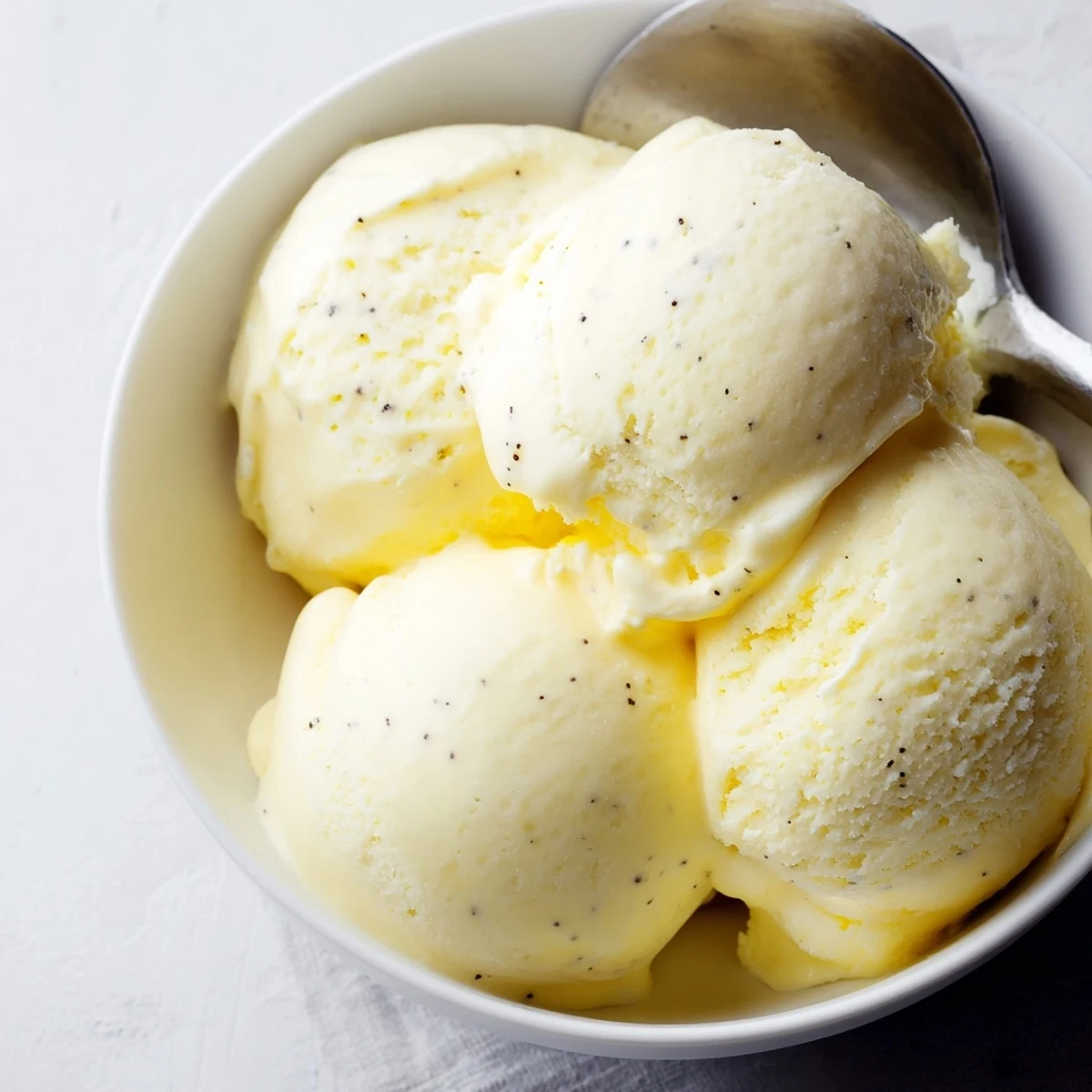 Scoop of rich vanilla ice cream garnished with fresh mint leaf on a wooden board