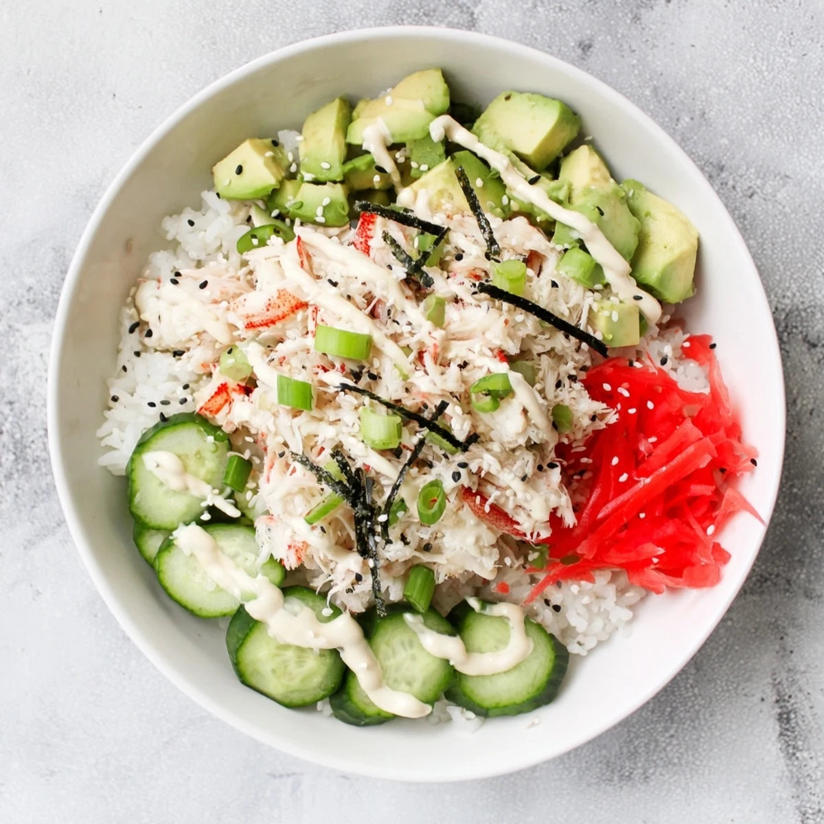 Vibrant deconstructed California roll sushi bowl drizzled with spicy mayo and toasted sesame seeds