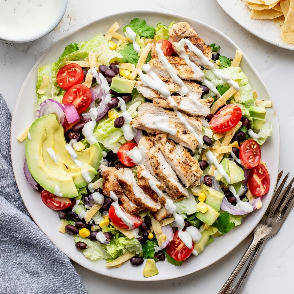 Vibrant layered southwestern chicken salad featuring spiced grilled chicken over crisp romaine, tomatoes, and creamy yogurt dressing