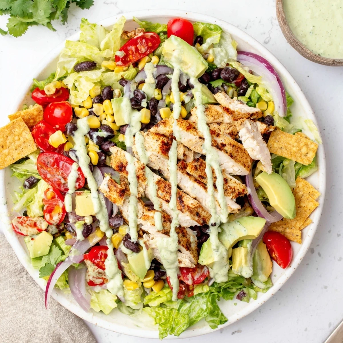 Fresh southwestern chicken salad plated with juicy sliced chicken breast, colorful vegetables, beans, and tortilla strips