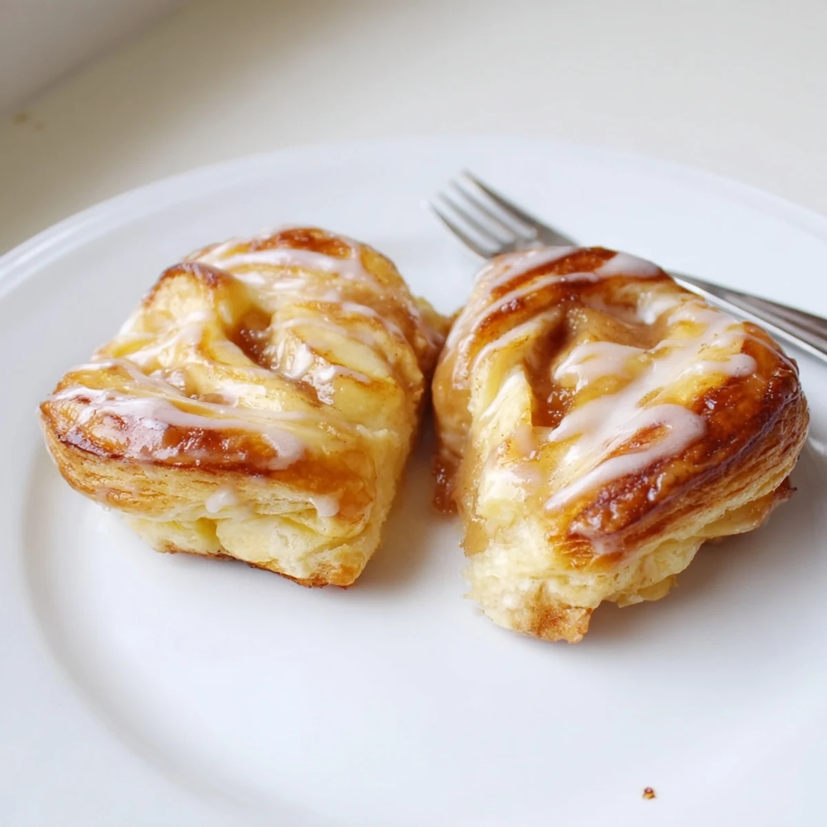 Golden apple cheese danishes drizzled with white icing on a wooden board  