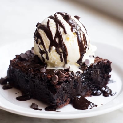 Decadent Chocolate Brownie Sundae with Hot Fudge Sauce, featuring fudgy brownie squares, whipped cream, and chopped nuts on a rustic table.