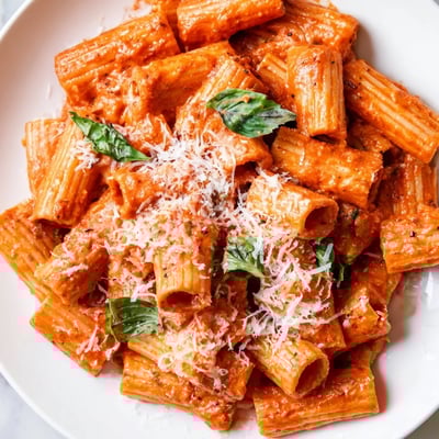 Steaming Creamy Tomato Pasta with Fresh Basil Leaves on a rustic table, paired with a glass of white wine.