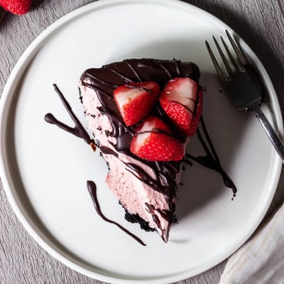 Freshly baked Chocolate Covered Strawberry Cheesecake with a chocolate cookie crust, creamy pink filling, and a decadent chocolate topping.