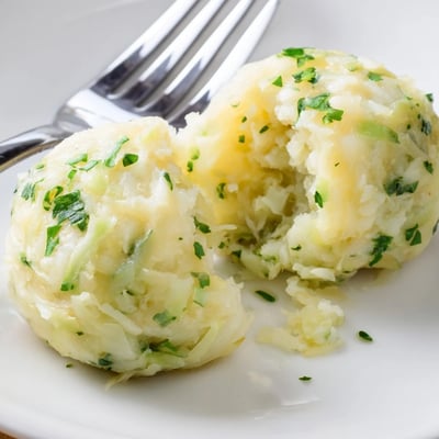 German Cabbage Dumplings simmered in broth with a ladle and fresh cabbage nearby.