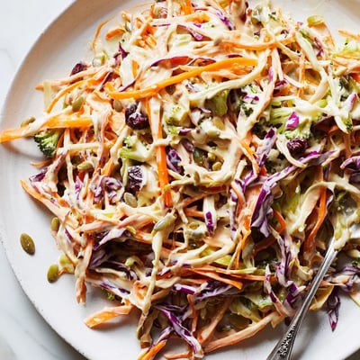 Crisp broccoli slaw topped with sunflower seeds and dried cranberries in bowl